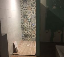 Carreaux de ciment dans la douche, carrelage blanc aux murs et carrelage effet parquet au sol de la salle de bain