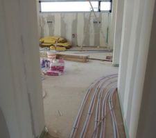 Les enduits progressent et les tuyaux d'eau courent sur le sol en attendant la mousse polyuréthane.