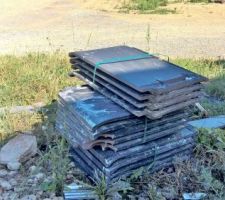 Tas de tuiles salies et cassées abandonné sur le devant de la maison.