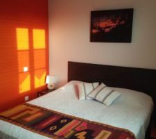 APRES : Chambre orange aux couleurs du Pérou dans laquelle nous avons déplacé le lit pour gagner de la place et fait une tête de lit avec des lames de parquet restantes collées sur une planche. Bordure de la tête de lit faite avec des baguettes d'angle peintes en noir.