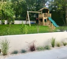 Terrasse bétonnée, graminées, et aire de jeux de notre fille