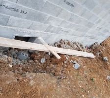 Planche de soutien des pignons abandonnée au sol avec serre-joint et morceaux de parpaing