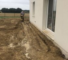 Tassement de la terre tout autour de la maison et du garage pour la réalisation du trottoir, de l'allée et de la terrasse.