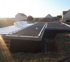 Les maçons ont enduit le vide sanitaire qui sera enterré, d'une couche imperméable. La ils commencent l'isolation de la dalle.