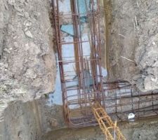 Ferraillage des semelles filantes. Les ferrailles sont calées par des éclats de parpaings. Un peu d'eau au fond de la tranchée