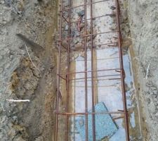 Ferraillage des semelles filantes. Les ferrailles sont calées par des éclats de parpaings. Un peu d'eau au fond de la tranchée