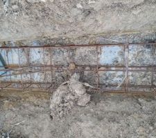 Ferraillage des semelles filantes. La ferraille touche le sol et les côtés s'effondrent un peu dû aux conditions météo et au type de sol plutôt sableux. Le maçon m'explique qu'il va dégager ces chutes de terre à la pelle avant le coulage du béton.