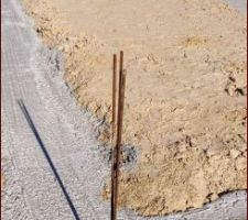 La dalle a subi la canicule de la semaine dernière. Elle doit être bien sèche désormais !
On observe 4 bouts d'armatures métalliques plantées dans la semelle de béton.