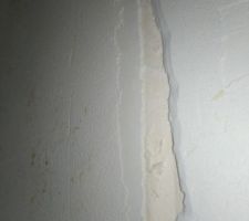 Fissure sur une bande entre une cloison placo et un mur béton.