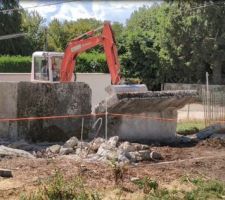 1ère prise en main de la minipelle, on pousse les sections de mur. En général le mur se casse en 2 sur la hauteur. La 1ère section est bien tombée, ici le haut de la 2ème section tombe. En revanche le bas ne voudra pas bouger, il faudra le heurter avec l'engin et la lame de nivellement.