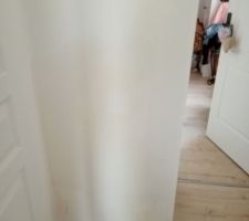 Cloison jaunie - la porte ouvre vers les WC