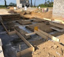 Terrassement avec les tranchées ou vont se trouver les murs porteurs. Ils ont mis du ciment au fond des tranchées pour pouvoir poser les ferraillages