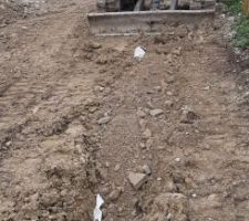 Remblaiement de la tranchée ouverte avec du concassé béton sec. On n'a pas de quoi tasser dans la tranchée, donc on fait ce qu'on peut en tapotant avec la pelle, mais ça ne vaut pas un pilonneur thermique. Tant pis, on fera ça avec le rouleau compresseur, ça ira bien.