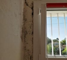 Fissure profondes sur le c&ocirc;t&eacute; de la fen&ecirc;tre rev&ecirc;tement b&eacute;ton et derri&egrave;re brique