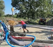 Versement des galets pour le hérisson. Comme pour le 0/100, on le transporte avec le seau de la grue et on étale à la main.