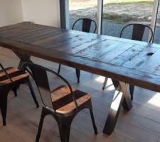 Aménagement du séjour avec la table en bois et pied en croix en acier.