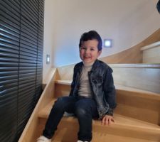 Escalier avec lumière au mur et store contre la tierce de la porte d'entrée n'oubliant pas ma beauté mon fils