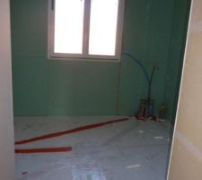 La salle de bain avec les plaues posées au sol et les tuyaux d'eau