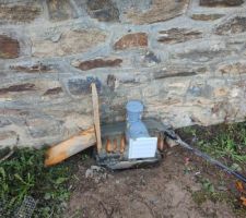 L'autre des 2 regards de la cave donnant sur l'extérieur.

C'est la seconde partie de mon bricolage d'aération de la cave.
Ici, on a un tube PVC de 100 avec les bons coudes pour traverser les 50cm du mur, et remonter un peu pour être au plus haut de la cave. 

Côté cave j'ai mis un extracteur d'air de VMC premier prix, 11W et 70m3 d'air extrait par heure, il fait un petit bourdonnement quand on est proches mais rien de bien méchant. Si ça marche bien, mais que le bruit nous ennuie, je remplacerai par quelque chose de plus silencieux.

Pour l'instant il est alimenté sur prise avec un interrupteur classique, j'ai commandé un interrupteur différentiel de température pour l'arrêter quand la différence entre cave et extérieur est trop forte (j'ai vu ça sur un forum et ça me paraissait pas con).

L'air humide remontant, l'extracteur le sort, et il passe par la sortie PVC blanche qu'on voit ici. J'ai mis du PVC car en inox c'était pas donné, je voulais d'abord m'assurer que le bricolage soit fonctionnel. Si ça marche, on mettra une sortie en inox plus esthétique.

L'idée ici c'est aussi de faire un coffre en briquette + pierre pour que ça soit plus propre, et probablement de la mettre un peu plus haute par rapport au sol (mais j'avais utilisé tout mon PVC, donc pas possible de faire plus haut pour la première tentative).

C'est en place depuis ce weekend, j'y retourne dans un mois, on verra si ça a changé quelque chose à l'humidité de la cave et à l'odeur. On croise les doigts !

(on ne se moque pas sur le coffrage svp, c'était mon premier. Promis depuis je regarde plein de vidéos et de tutos pour faire moins dégueulasse !)