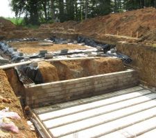 Vue du mur séparant le sous-sol partiel (premier plan) et le futur vide sanitaire. On distingue bien les marques laissées par la pelle mécanique qui a creusé la fouille du sous-sol.