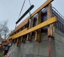 Mise en place du panneau extérieur à la grue. Il faut le soutenir avec des étais (surtout pour le poser à la bonne hauteur, et droit), poser des serre-joints en partie haute et des tiges et écrous de coffrage en partie basse pour le fixer définitivement avant de décrocher la grue.