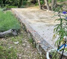 Muret béton recouvert de pierres récupérées dans le terrain.