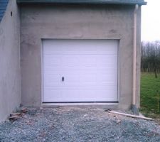 La porte de garage vient d' être posée . Le  menuisier teste le manque de lumiére dans la garage . On va lui ouvrir la porte ..