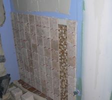 Pose du travertin sur le mur de la douche italienne