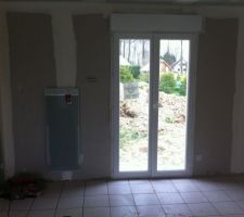 Porte fen&ecirc;tre et panneau rayonnant de la salle &agrave; manger, vu sur l'arri&egrave;re de la maison, carrelage en cour, en attente des joins.