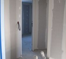 Vue sur petit couloir desservant deux chambres dont une visible ici, accessible en haut à droite de l' escalier
