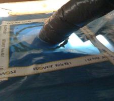 Détail du passage du tuyau de VMC au travers du pare-vapeur. Un trou dans le pare-vapeur, raccord à la bouche installée dans le faux-plafond. L'étanchéité est assurée par une rustine découpée dans le rouleau de pare-vapeur, passée autour du tuyau puis mastiquée, scotché sur le pare-vapeur et le tuyau.