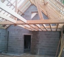 Vue du salon sur le solivage bois au-dessus de la cuisine et de la passerelle arrivant de la mezzanine et amenant au palier.