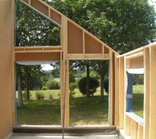 On voit l'ossature (145*45mm) et le contreventement en bois respirant de 22mm, le pare-pluie bleu protégeant les ouvertures, les réservations de 250 mm dans l'ossature pour les volets