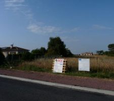 Terrain en premier plan avec panneaux de d&eacute;claration pr&eacute;alable et permis de construire.