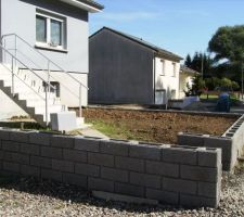 Mise en place du muret devant la maison, ajout de terre pour arriver au niveau du muret. En attente du niveau fini par rapport au trottoir pour faire le pavage.