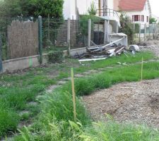 Vue du terrain par l'arri&egrave;re
La vue donne vers la rue et le muret du voisin de droite.
On peut voir les poteaux pour la construction