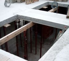 Trémie et ferraille en attente pour escalier en béton et plus loin vide de hall