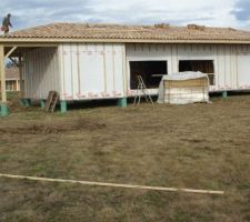 La maison est hors d'eau. On voit devant la palette d'osb pour le sol de la maison.
On voit également les 4 poteaux en bois qui portent la toiture. On a demandé des poteaux en acier...