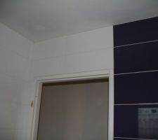 Au dessus de la porte de la SDB enfants. L'interrupteur sortira bien sur la bande violette