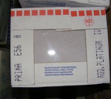 La faience du bas de la salle de bains qui sera séparé d'une frise grise avec des motifs chromés