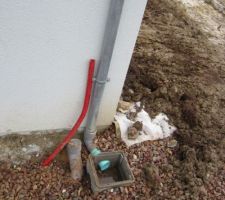 Regard eaux pluviales ; à sa gauche, un tuyaux d'évacuation des eaux usées ; la gaine rouge contiendra le fil d'alimentation électrique pour la pompe située dans la cuve de récupération d'eau de pluie.