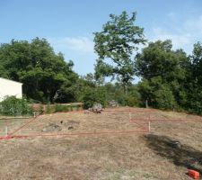 Implantation d'une maison en L avec en rouge la maison et en noir l'abris voiture.