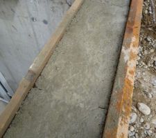 Mur de sortie de cave réhaussé d'une rangée de parpaing. Avant la mise en oeuvre de la chape, humidification   saupoudrage de ciment pour lier avec le mortier de la chape