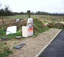 Sur cette photo, nous observons en bas &agrave; gauche la borne rouge du g&eacute;om&egrave;tre.
Dans le fond, en haut &agrave; droite, nous observons un poteau de bois correspondant &agrave; la fin de notre fa&ccedil;ade.
Un m&egrave;tre a &eacute;t&eacute; tendu entre les deux bornes du g&eacute;om&egrave;tre. La borne EDF a &eacute;t&eacute; plac&eacute; dans le terrain... La bouche des eaux pluviales/us&eacute;es a &eacute;t&eacute; plac&eacute; sur la limite du terrain... Des gros cailloux de la mairie ont &eacute;t&eacute; d&eacute;plac&eacute; &agrave; cheval sur le terrain et le trottoir... La route est &agrave; moiti&eacute; goudronn&eacute;e... Quelqu'un a d&eacute;pos&eacute; un monticule de d&eacute;chets sur le terrain (butte envahi par la v&eacute;g&eacute;tation derri&egrave;re la borne EDF)...
