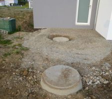 Remblaiement de la sortie arrière du garage avec du concassé 7/15   dégagement du couvercle du puit de rejet de la PAC. Au premier plan, le puit perdu des eaux pluviales