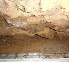 Voici une vue plongeante du vide entre le mur de pierre et la dalle de b&eacute;ton. On aper&ccedil;oit un rail m&eacute;tallique au fond.