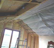 L'isolation des murs et rampants avec de la laine de verre encastrée entre les montants, suivie de la pose de la membrane d'étanchéité à l'air, à soigner tout particulièrement pour obtenir un résultat optimal.