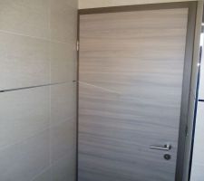 Porte de la salle d'eau du RDC en harmonie avec le carrelage et les baguettes inox
