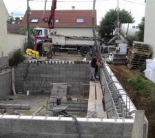 L'&eacute;quipe est en train de proc&eacute;der au coulage du b&eacute;ton dans la partie int&eacute;rieure des blocs, sur la totalit&eacute; de la hauteur des parois de la cave (il faut noter que l'isolant est continu &agrave; l'ext&eacute;rieur des parois)