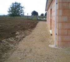 Face ouest avec une allée en caillou afin de pouvoir faire le tour de la maison les pieds au sec et pour protéger le futur enduit des projections de terre lorsqu'il pleut.